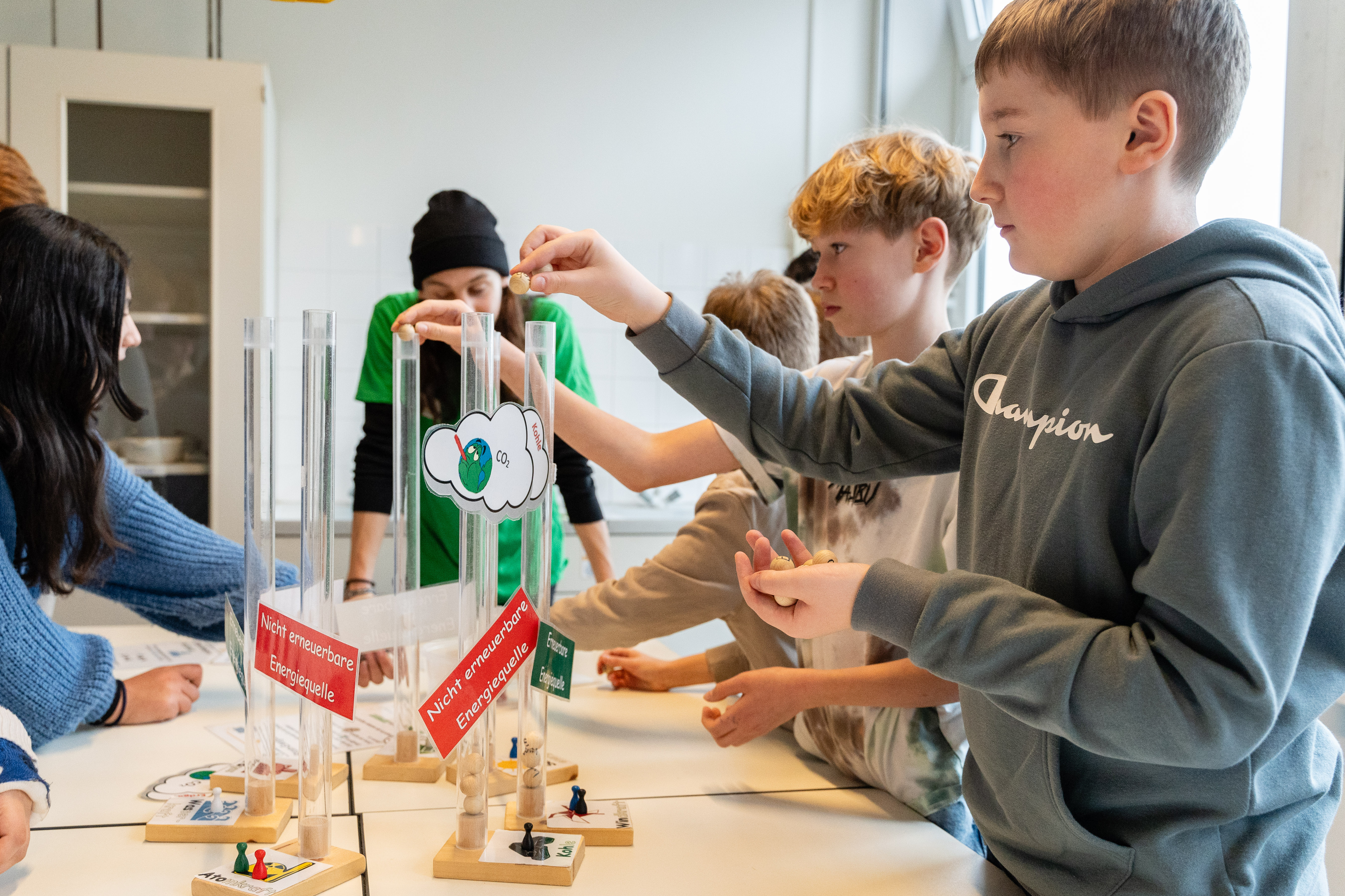 Mehrere Schüler lassen Holzkugeln in verschiedene Röhren fallen.